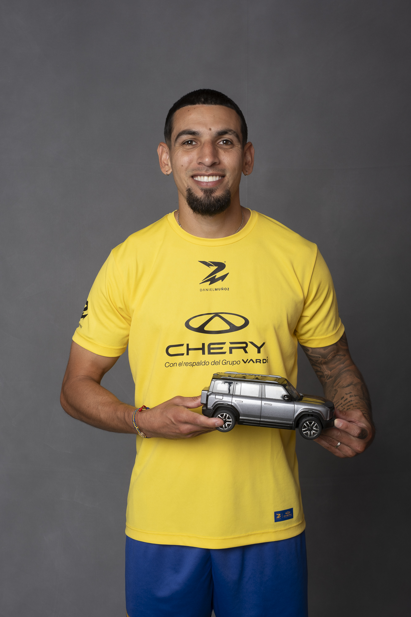 Daniel Muñoz con camiseta amarilla de Chery Colombia sosteniendo una maqueta de la iCAR 03 durante su presentación como embajador de la marca